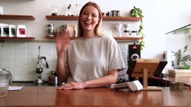 Усміхнена Блондинка Бариста Махає Камеру Кафе — стокове відео