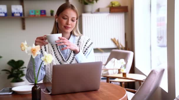 Wesoła Blondynka Pijąca Kawę Oglądająca Laptopa Kawiarni — Wideo stockowe