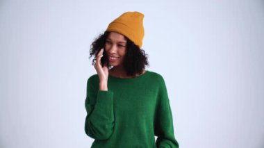 Gri stüdyoda telefonla konuşan neşeli kıvırcık saçlı kadın.