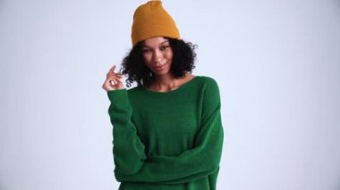 Güzel kıvırcık saçlı kadın gri stüdyoda kameraya bakıyor.