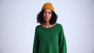 Gri stüdyodaki kameraya evet diyen kıvırcık saçlı kadın.