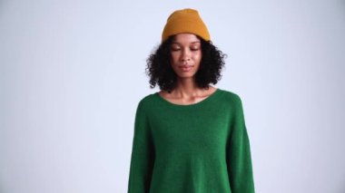 Yoğunlaşmış kıvırcık saçlı kadın gri stüdyoda kameraya gözlerini açıyor.