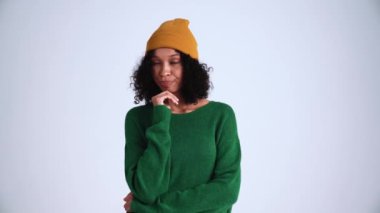 Meditasyon yapan kıvırcık saçlı kadın gri stüdyoda bir şey düşünüyor.