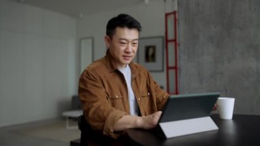 Evde tabletle yazan pozitif Asyalı adam