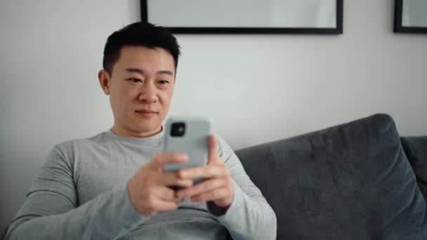 Positieve Aziatische Man Sms Telefoon Thuis — Stockvideo