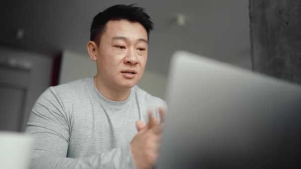 Aziatisch Geconcentreerde Man Praten Door Video Oproep Laptop Thuis — Stockvideo