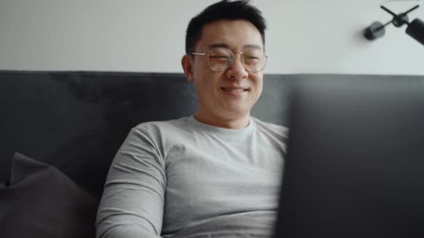 Glimlachende Aziatische Man Het Dragen Van Bril Rond Kijken Laptop — Stockvideo