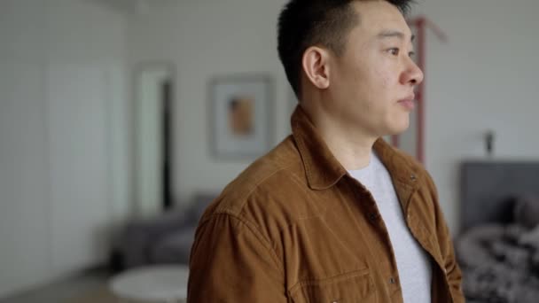 Griner Asiatisk Mand Iført Afslappet Klud Ser Kameraet Derhjemme – Stock-video