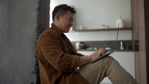 Positiver Asiatischer Mann Lässiger Kleidung Tippt Hause Auf Laptop — Stockvideo