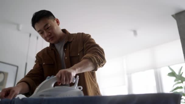 Positive Asian Man Ironing Clothes Home — Video