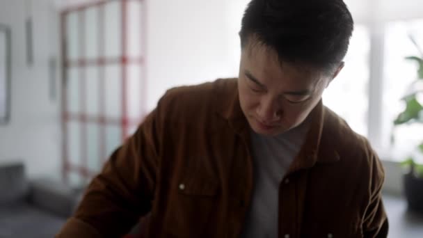 自信を持ってアジア人男性アイロン服に家 — ストック動画