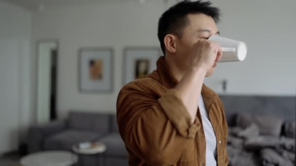 Smiling Asian Man Wearing Casual Cloth Drinking Coffee Home — Vídeo de Stock