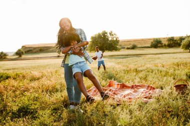 Siyah mutlu anne piknik sırasında yaz sahasında oğluyla oynuyor.