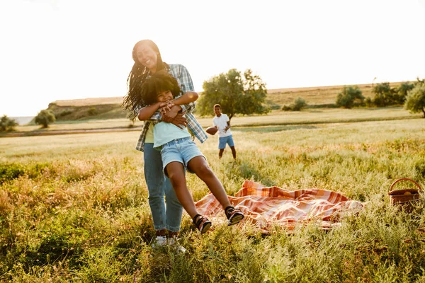 Siyah mutlu anne piknik sırasında yaz sahasında oğluyla oynuyor.