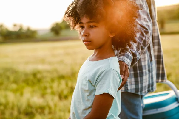 Siyah kıvırcık çocuk annesiyle yaz tarlasında yürüyor.