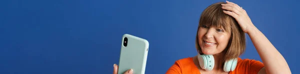 Senior Blond Kvinne Med Hodetelefoner Som Tar Selfie Mobil Isolert – stockfoto