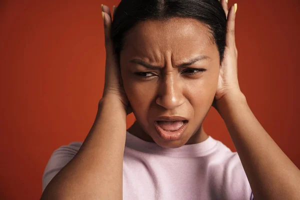 Young African American Woman Frowning Covering Her Ears Isolated Red — стоковое фото