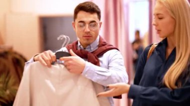 Neşeli çift kıyafet dükkanında ödeme için bir şeyler taşır.