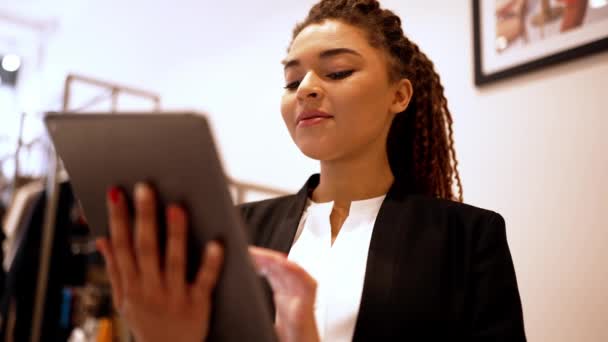 兴高采烈的非洲女店员在服装店里用平板电脑打字 — 图库视频影像