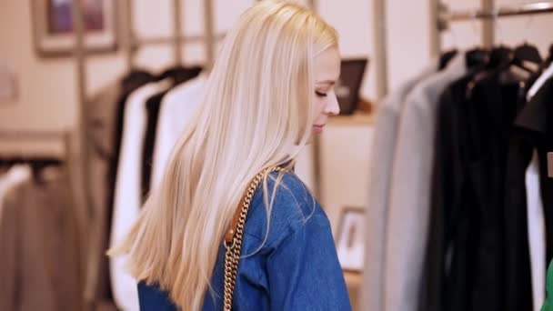 Positive Blonde Woman Chooses Clothes Clothing Store — Stockvideo
