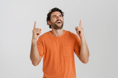 Genç esmer kadın gülüyor ve beyaz arka planda izole bir şekilde parmaklarını yukarı kaldırıyor.