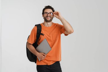 Sırt çantasıyla poz verirken gülen genç adam ve beyaz arka planda izole edilmiş egzersiz kitapları.