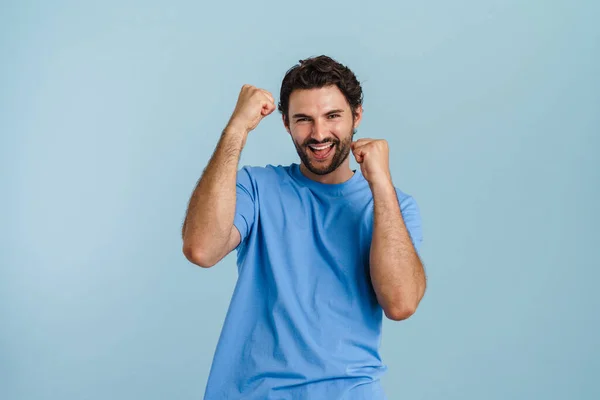 Junger Brünetter Mann Schreit Während Siegergeste Auf Blauem Hintergrund Macht — Stockfoto