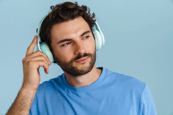 Młody Brunetka Człowiek Włosia Słuchanie Muzyki Słuchawki Izolowane Niebieskim Tle — Zdjęcie stockowe