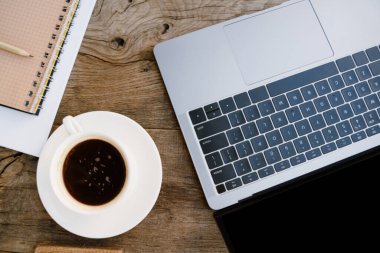 Laptop ve kahve fincanının fotoğrafı dışarıda, ahşap masada.