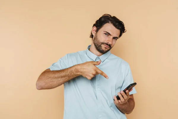 白发男人用手指指指着因米色背景而隔离的手机 — 图库照片