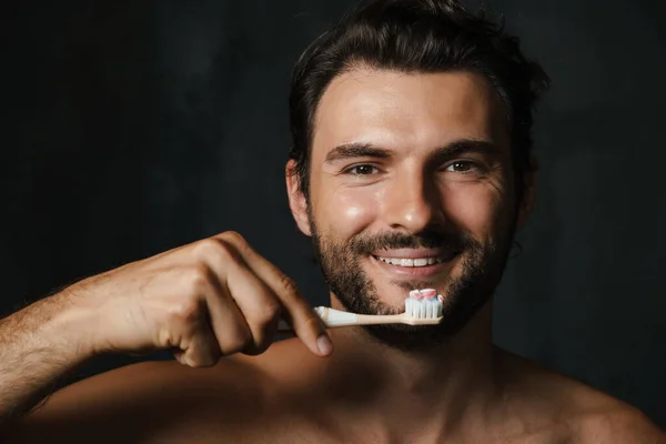 Młody Pół Nagi Mężczyzna Uśmiecha Się Myjąc Zęby Czarnym Tle — Zdjęcie stockowe