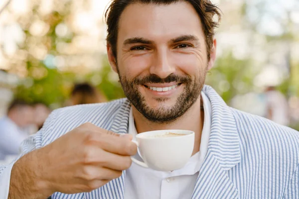 Joven Morena Hombre Sonriendo Bebiendo Café Mientras Está Sentado Cafetería —  Fotos de Stock
