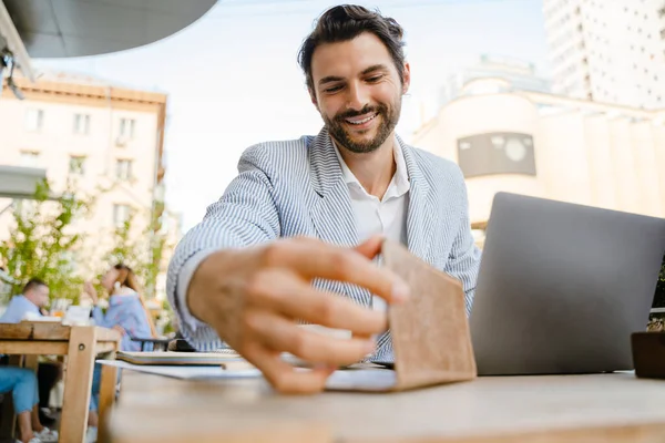 Young Brunette Man Looking Bill While Working Laptop Cafe Outdoors — Stockfoto