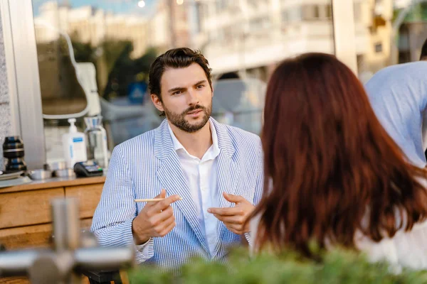 屋外のカフェでビジネスミーティング中に話す若い男性と女性 — ストック写真