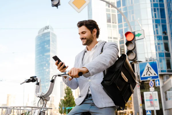 Joven Sonriendo Usando Celular Mientras Está Sentado Bicicleta Calle Ciudad —  Fotos de Stock