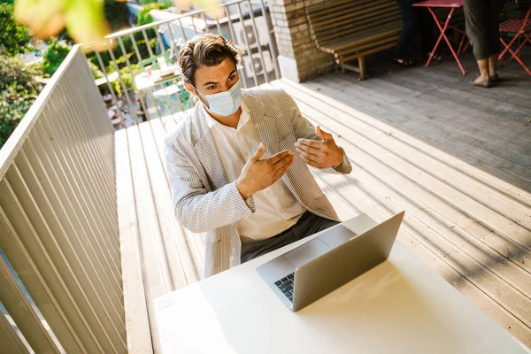 Jovem Máscara Facial Gesticulando Enquanto Trabalhava Com Laptop Café Livre — Fotografia de Stock