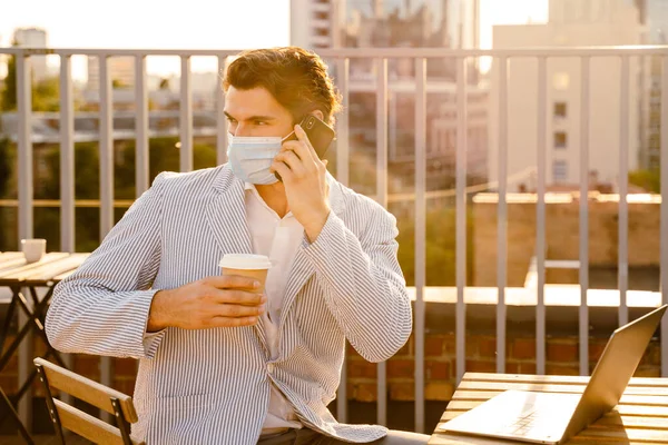 Young Man Face Mask Talking Cellphone While Working Laptop Cafe — 스톡 사진