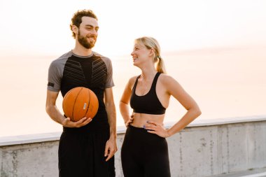 Genç bir adam ve bir kadın dışarıda birlikte top oynuyorlar.