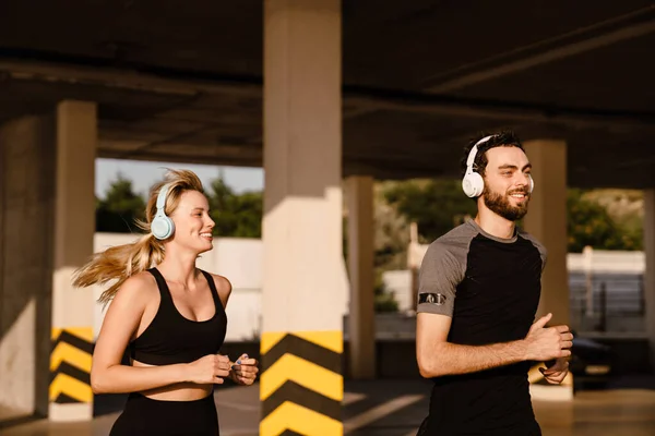 Young Man Woman Headphones Running Together Parking Outdoors — Stock Fotó