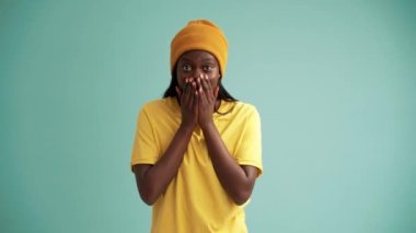 Turkuaz stüdyoda kameraya sevinen sürpriz Afrikalı kadın.