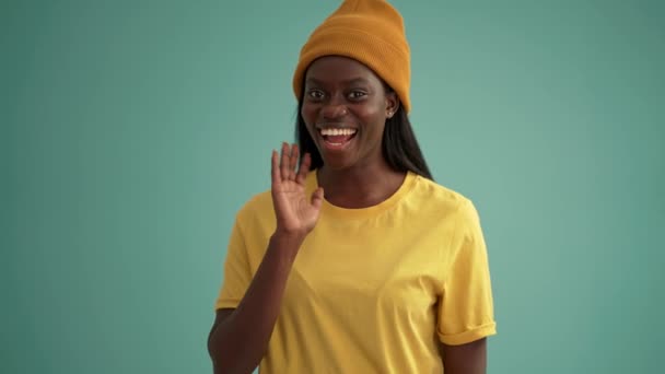 Smiling African Woman Showing Hello Gesture Turquoise Studio — Vídeos de Stock