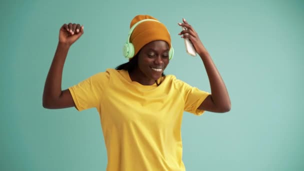 Rejoicing African Woman Wearing Headphones Dancing Turquoise Studio — Vídeos de Stock