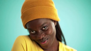 Turkuaz stüdyoda kameraya poz veren tatlı Afrikalı kadın.