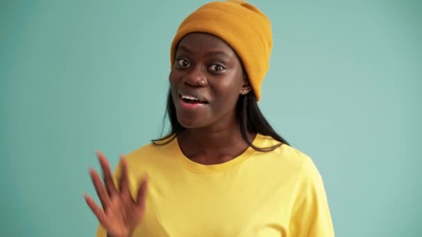 Cheerful African Woman Greeting Camera Turquoise Studio — стоковое видео