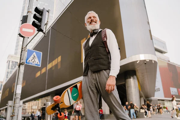 Grey Mature Man Smiling While Holding Skateboard While Walking City — Foto Stock
