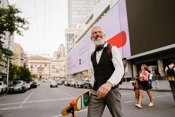 Grey Mature Man Smiling While Holding Skateboard While Walking City — Foto Stock