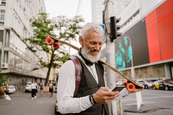 Uomo Maturo Grigio Utilizzando Telefono Cellulare Mentre Piedi Con Skateboard — Foto Stock