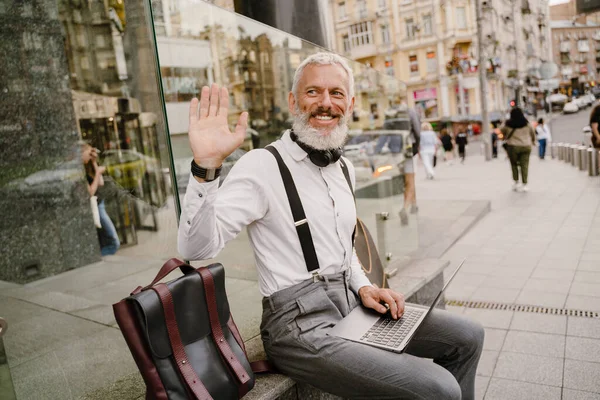 在城市街道上与笔记本电脑一起工作时 灰色的成熟男人摆姿势 — 图库照片