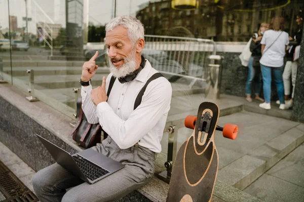 在城市街道上与笔记本电脑一起工作时 灰色的成熟男人摆姿势 — 图库照片
