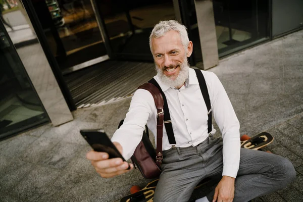 Grigio Maturo Uomo Prendendo Selfie Cellulare Mentre Seduto Skateboard Città — Foto Stock